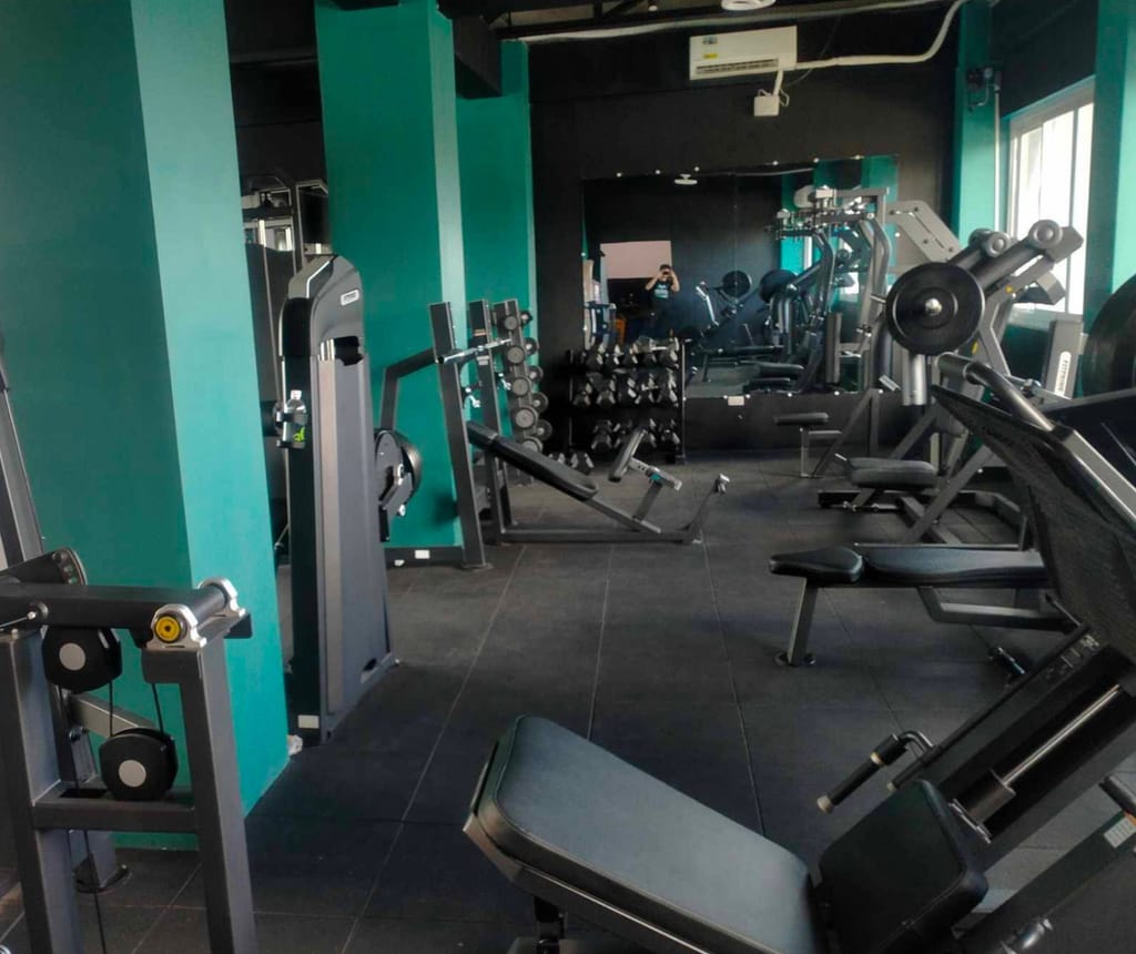 Pateros branch strength area with teal pillars, selectorized machines, benches and a dumbbell rack