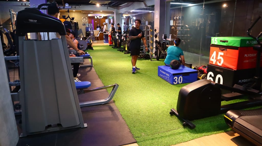 Busy Shaw Pasig Blvd. branch floor: a coach walks the turf lane while members train on machines and plyo boxes